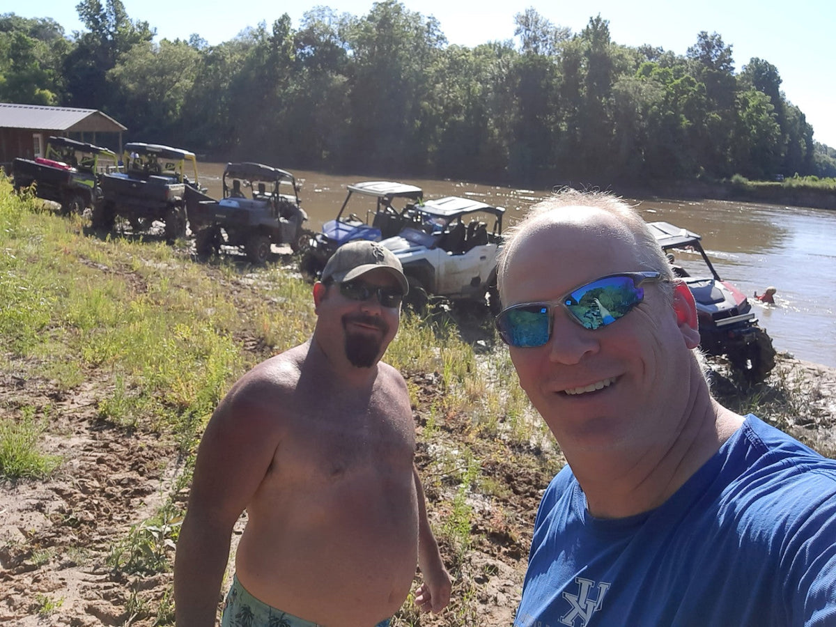 Bryan and a friend at a river sandbar with side-by-sides in the background