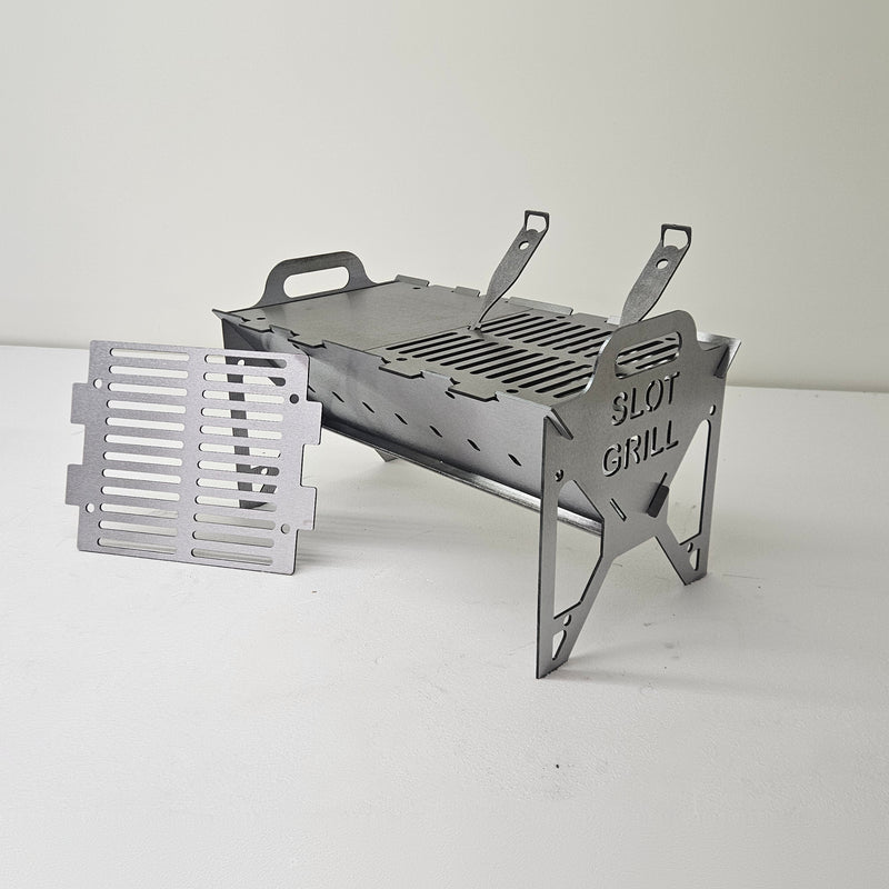 Slot Grill Full Size with a solid griddle plate on one half and a slotted grate on the other, spare grate beside it
